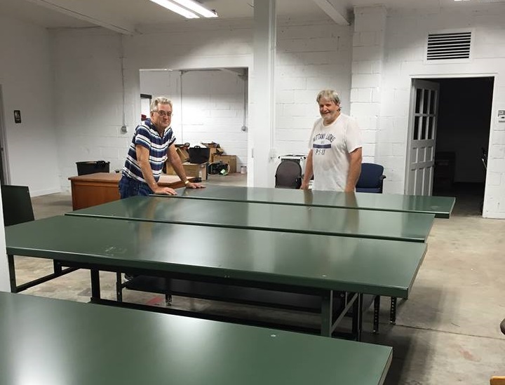 Ed and Roger, volunteers at Indianapolis, set up tables in the workspace